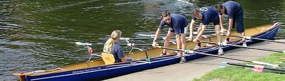 Drie roeiers stappen in een Baumgarten C3x+ instructie- en trainingsroeiboot
